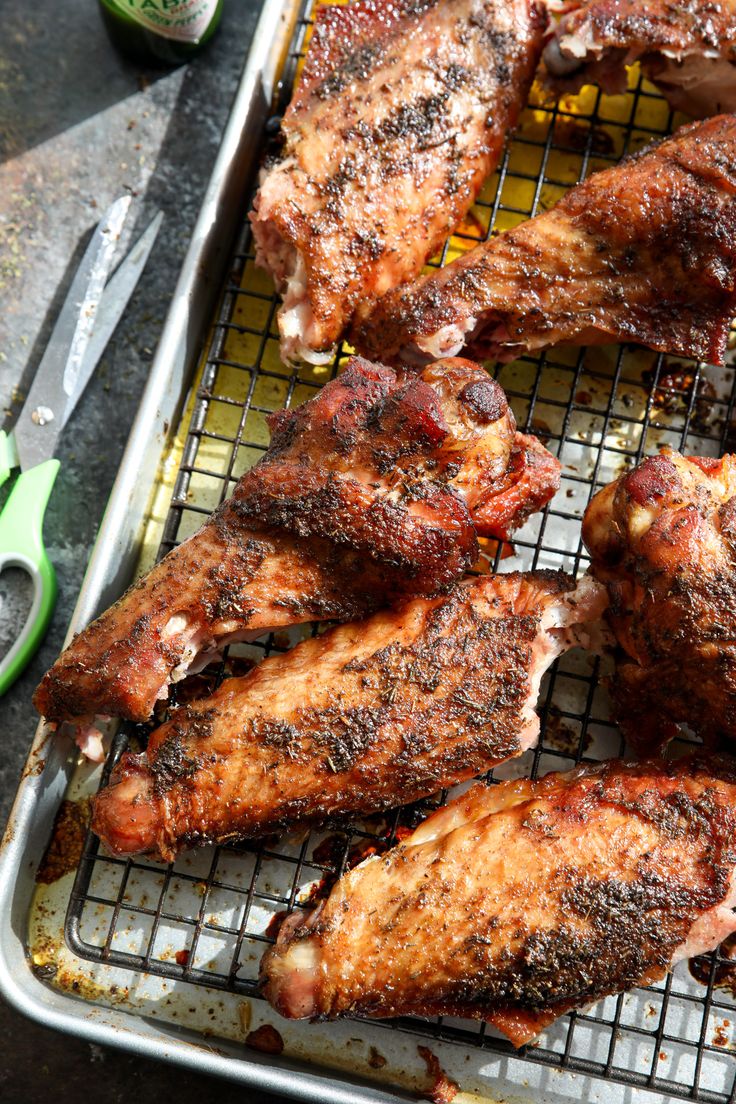 chicken wings on a grill with tongs and seasoning next to them, ready to be cooked