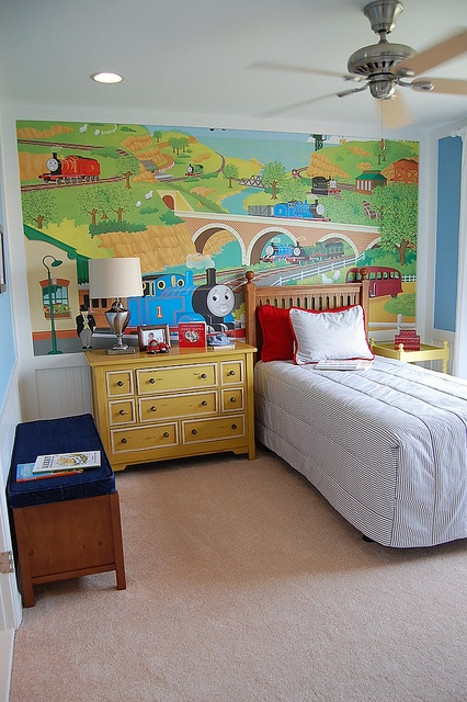 a child's bedroom with thomas the train mural on the wall and dressers