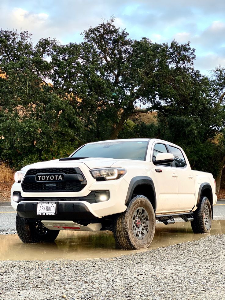 a white toyota truck driving down a dirt road