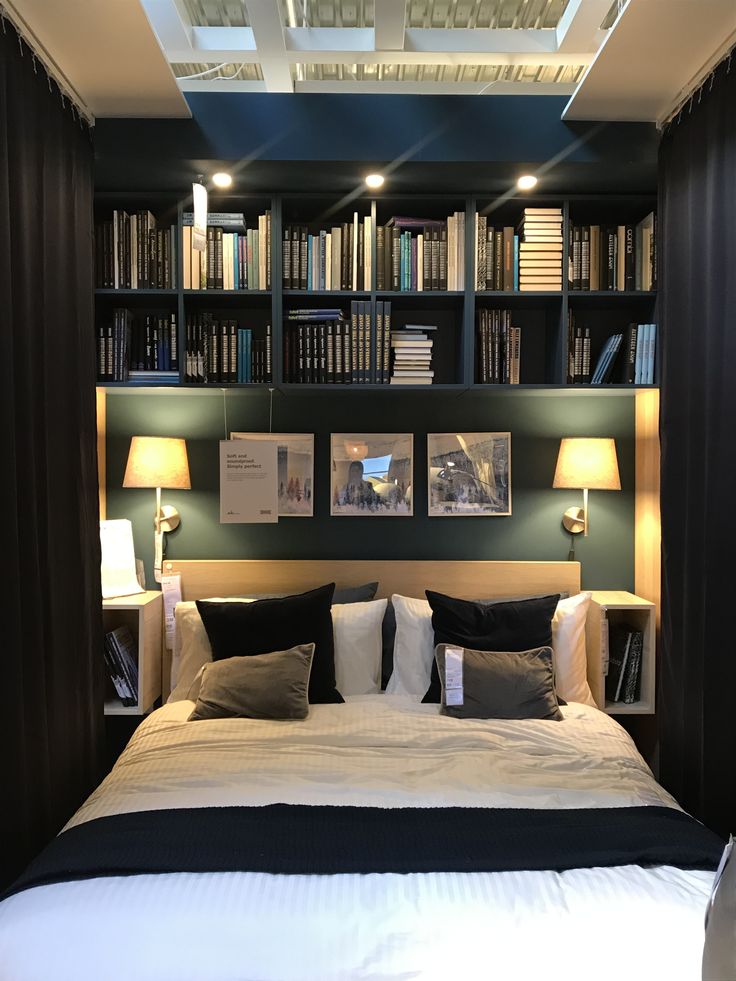 a bed sitting under a book shelf filled with books