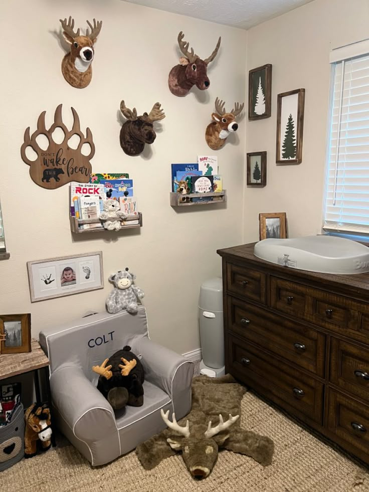 a baby's room with deer head mounted on the wall and stuffed animal toys