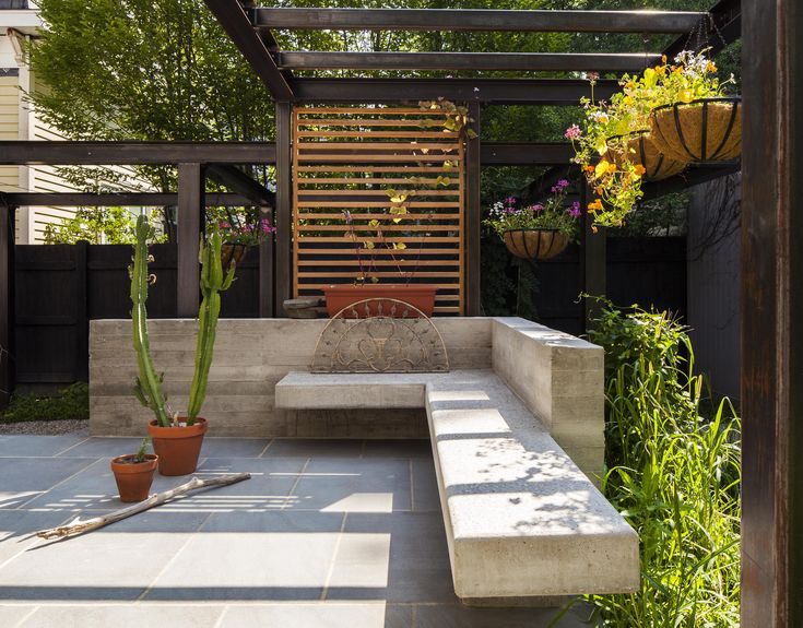 an outdoor seating area with potted plants on the side and a bench in the middle