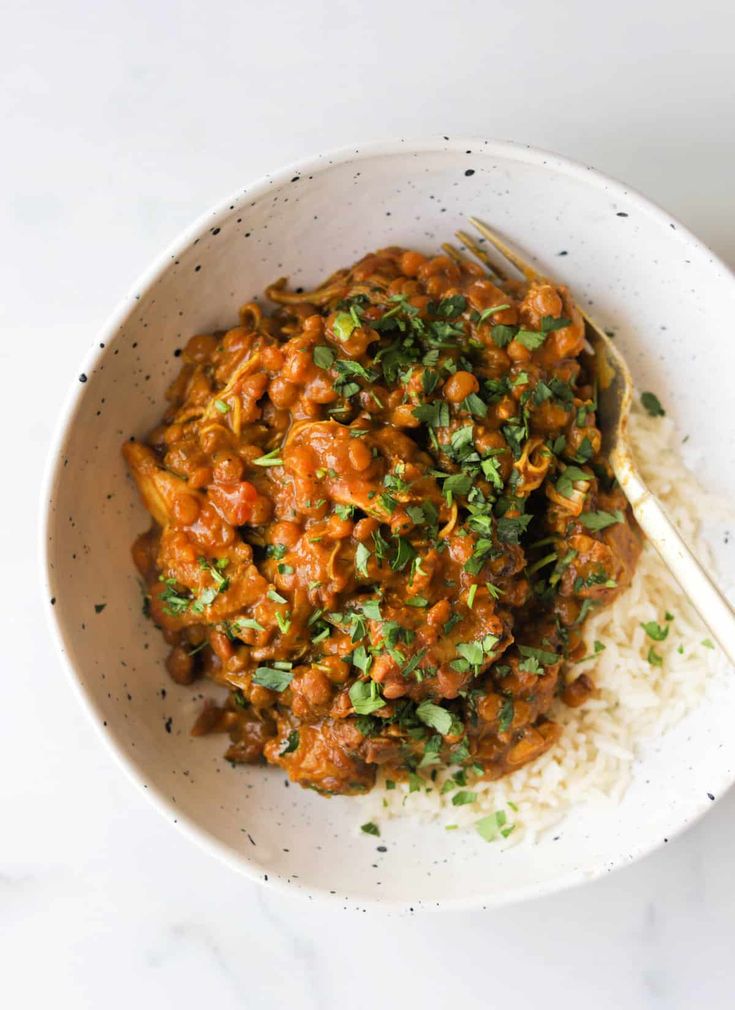 a white bowl filled with rice, meat and garnished with cilantro