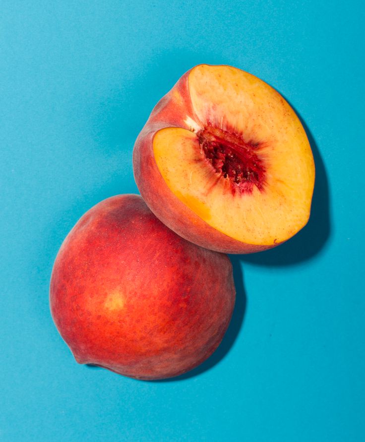 two peaches on a blue background with one cut in half and the other whole