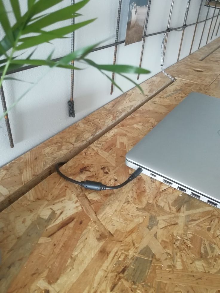 an open laptop computer sitting on top of a hard wood floor next to a plant