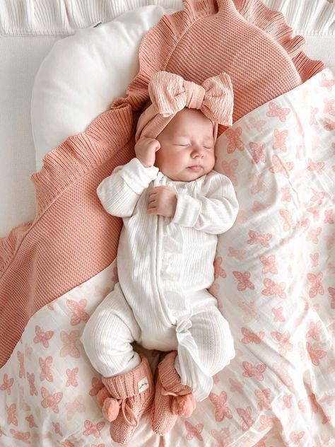 a baby is sleeping on a bed with pink and white sheets, pillows and blankets