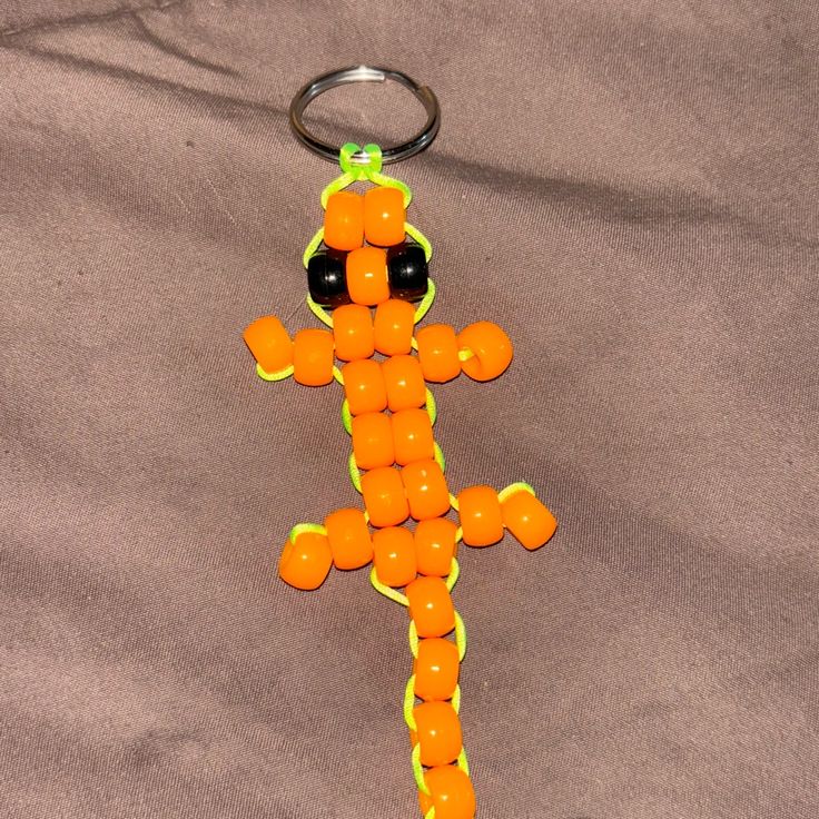 an orange and black keychain made to look like a lizard on a gray background