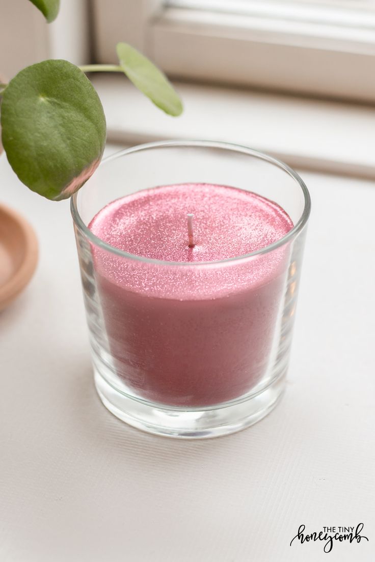 a pink candle sitting on top of a table next to a plant