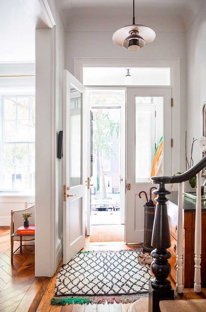 an entryway with a rug, light fixture and wooden stairs leading to the front door