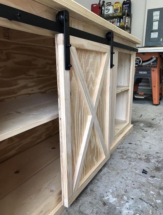 an unfinished cabinet with sliding doors and shelves