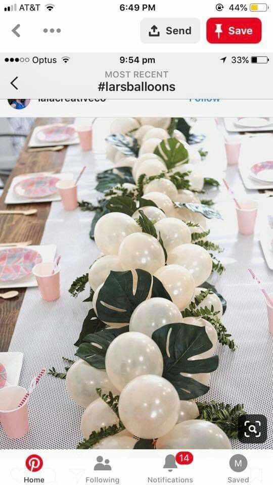 the table is set with balloons and greenery