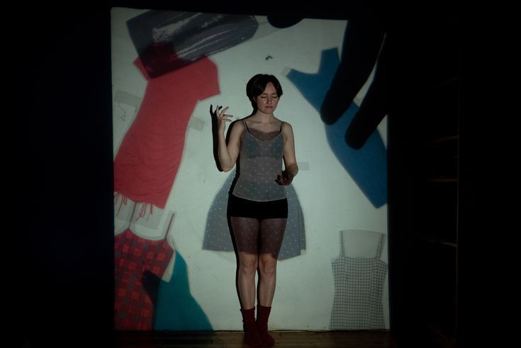 a woman standing in front of a wall with clothes on it