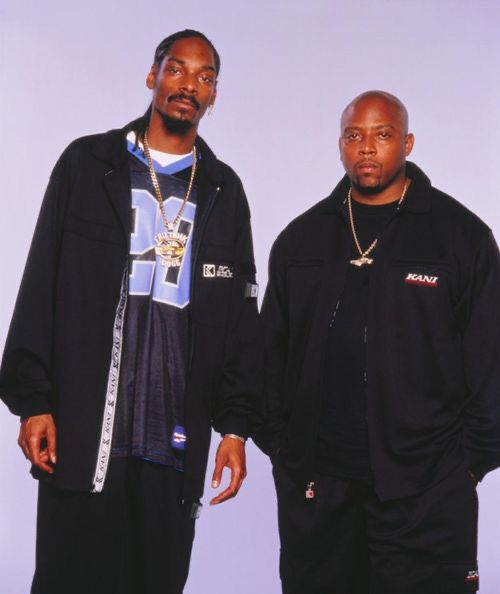 two men standing next to each other in front of a white background wearing black clothing