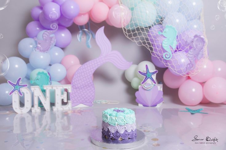 a little mermaid themed birthday party with balloons, cake and decorations in pastel colors