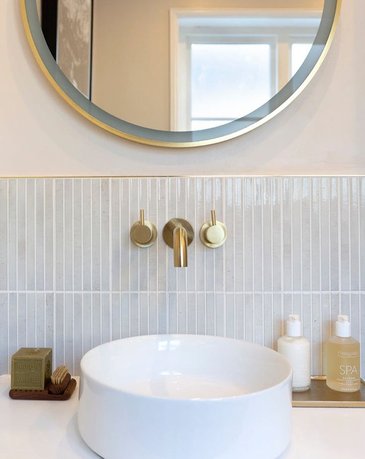 a bathroom sink with a round mirror above it