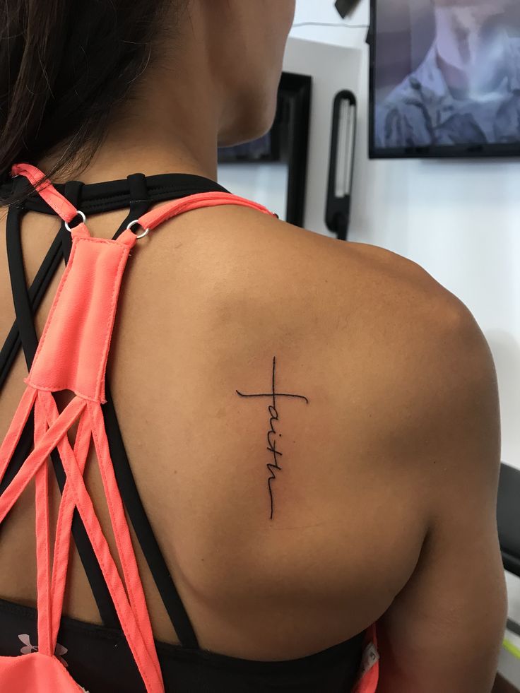 a woman with a cross tattoo on her upper back and the word faith written in cursive font