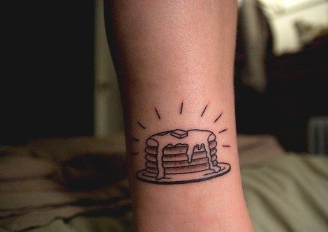 a small tattoo on the wrist of a person with a cake in front of them