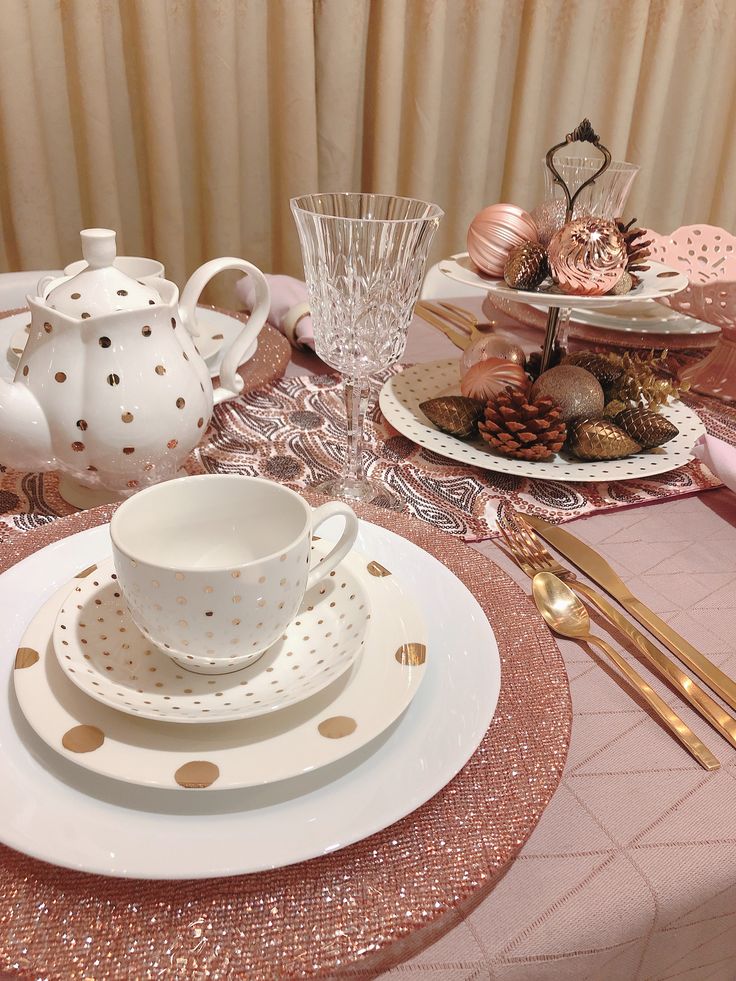 the table is set with pink and gold dishes