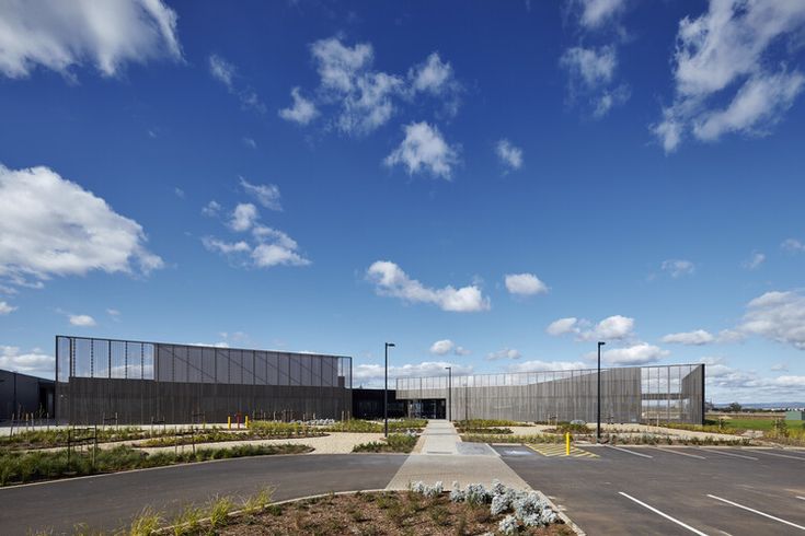 an empty parking lot in front of a large building with glass walls on each side