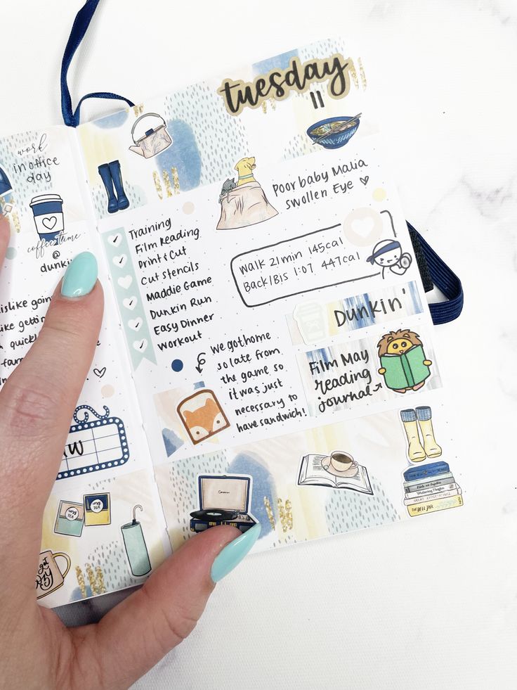 a hand holding an open planner book with stickers on it and writing in the pages