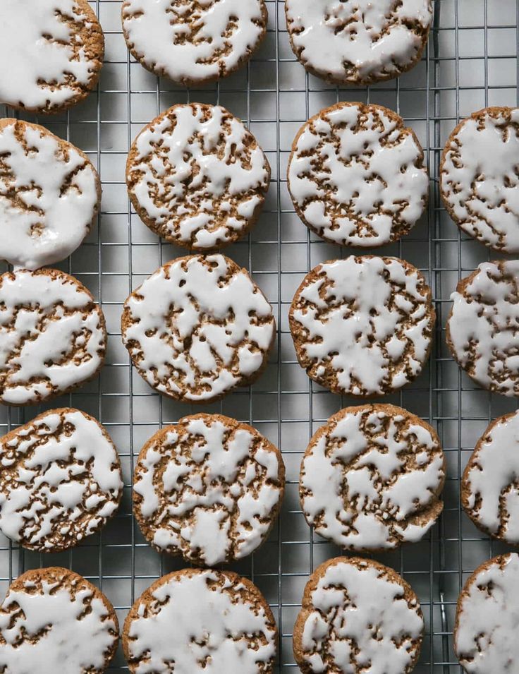 a cooling rack filled with iced cookies on top of a metal tray and covered in icing