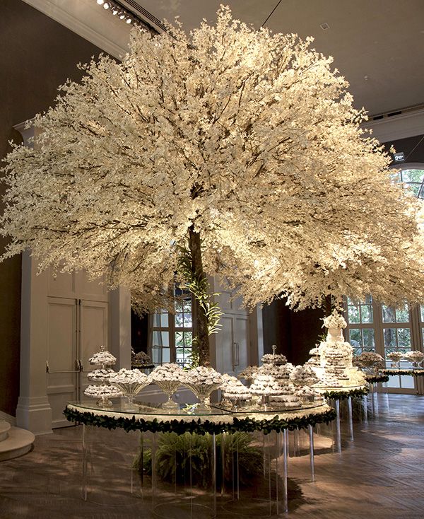 a large white tree sitting in the middle of a room filled with tables and chairs