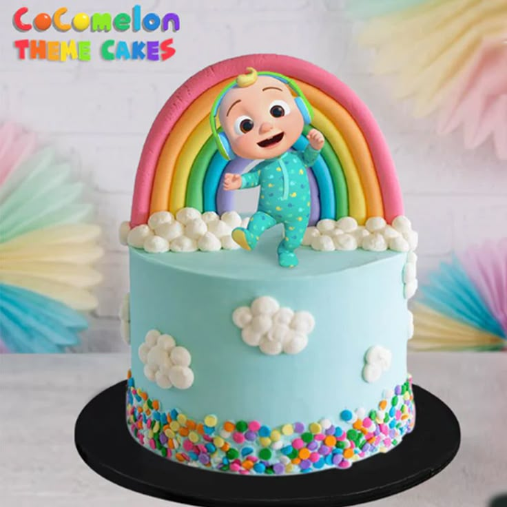 there is a cake with a baby on it and rainbow decorations in the background,