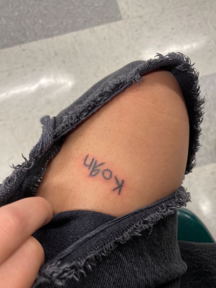 a person with a small tattoo on their arm that says kow in cursive writing