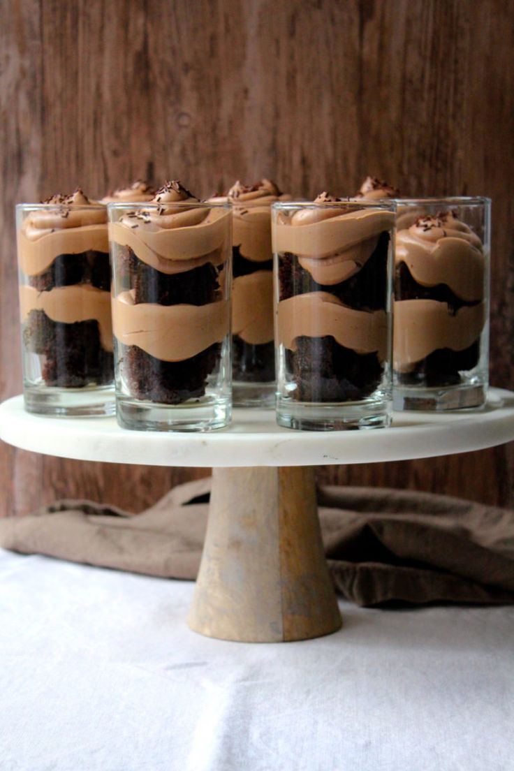 four glasses filled with brownies on top of a cake stand