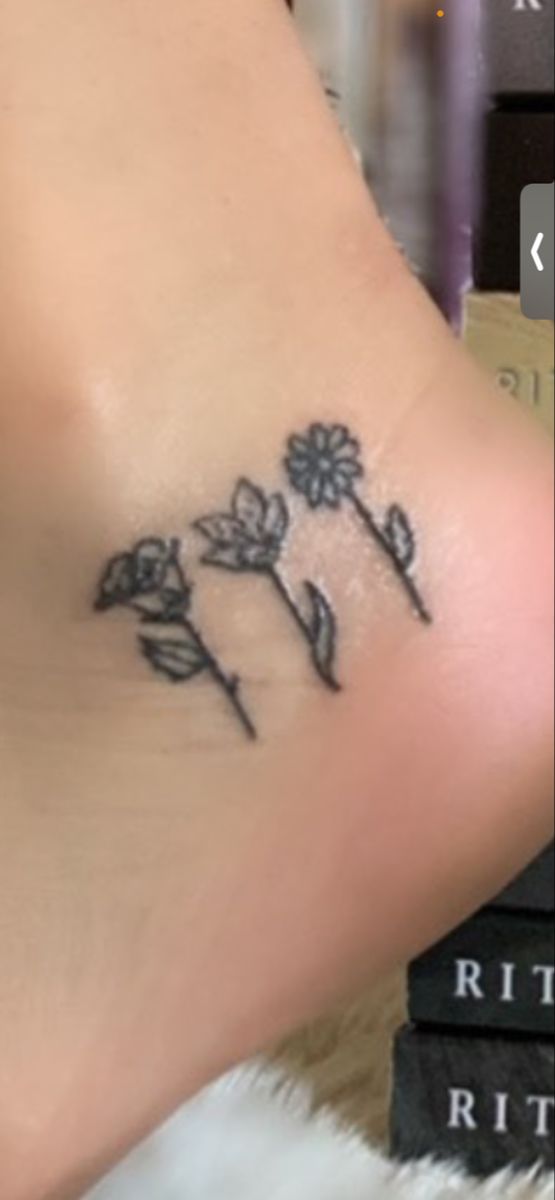 a small flower tattoo on the side of a woman's leg, with an arrow