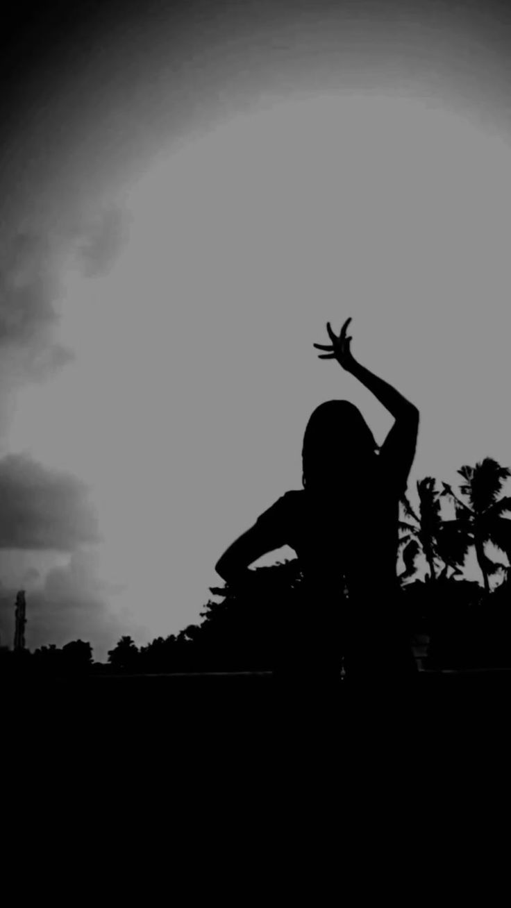 the silhouette of a person reaching up to catch a frisbee in the air