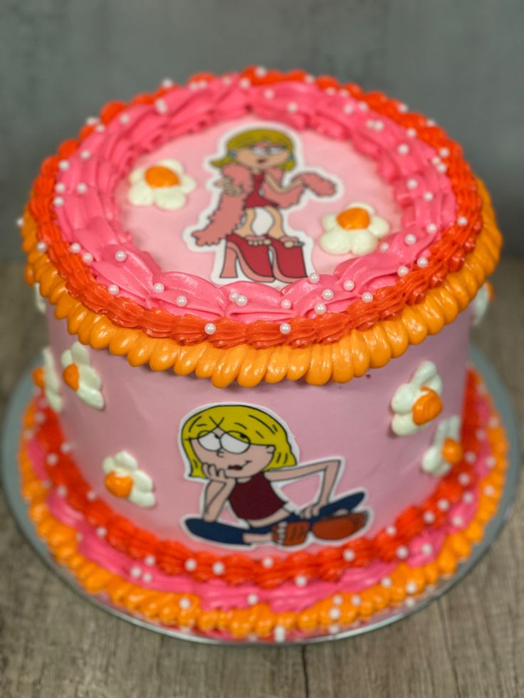 a pink cake decorated with cartoon characters on it's sides and an orange border around the edges