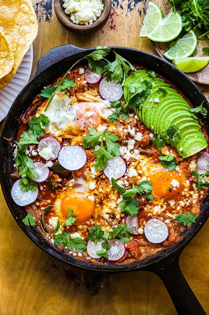 a skillet filled with mexican food on top of a wooden table next to tortilla chips