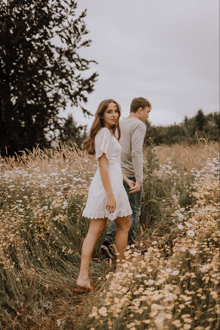 an engaged couple walking through the tall grass