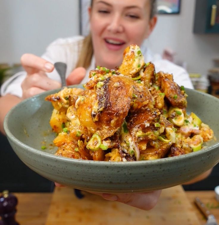 a woman is holding a bowl full of food