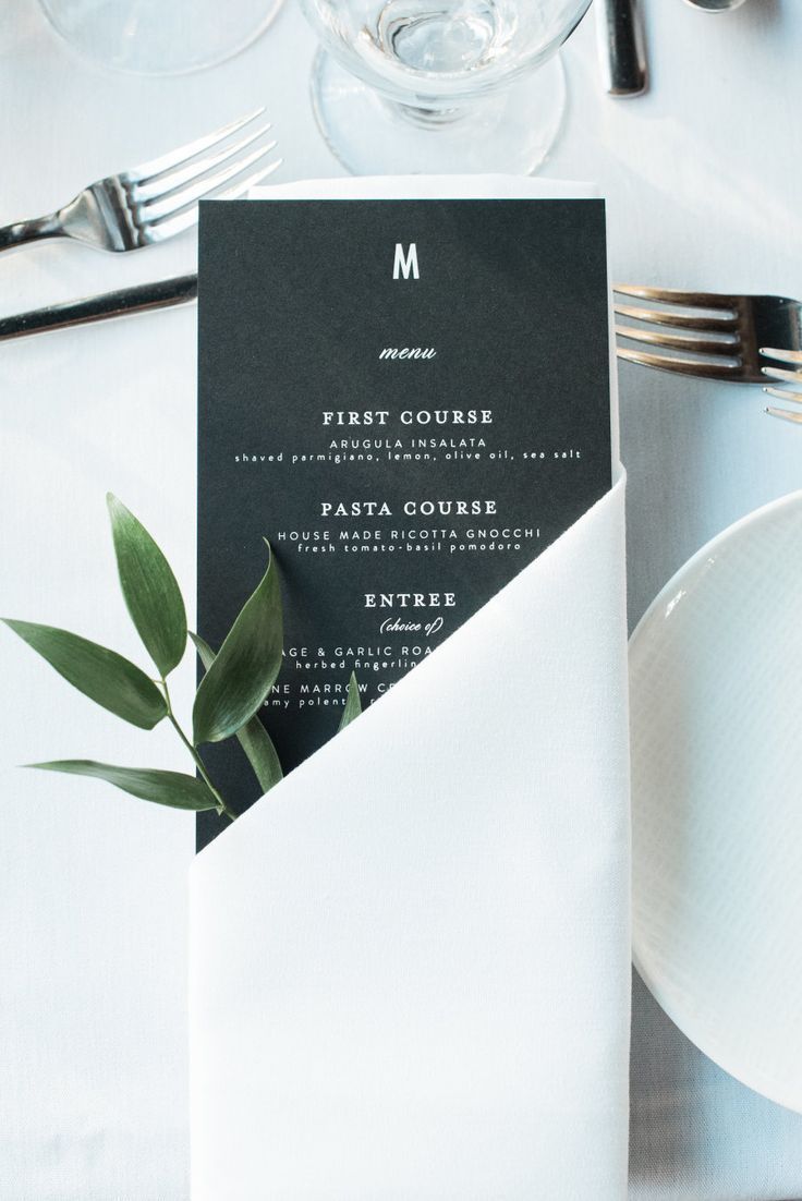 a table with white plates, silverware and napkins on it that has a menu in the pocket