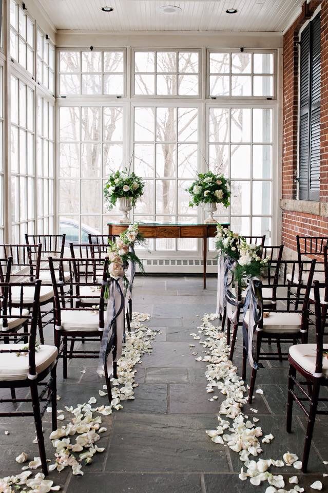 the aisle is decorated with white flowers and greenery as well as black chairs for an outdoor ceremony