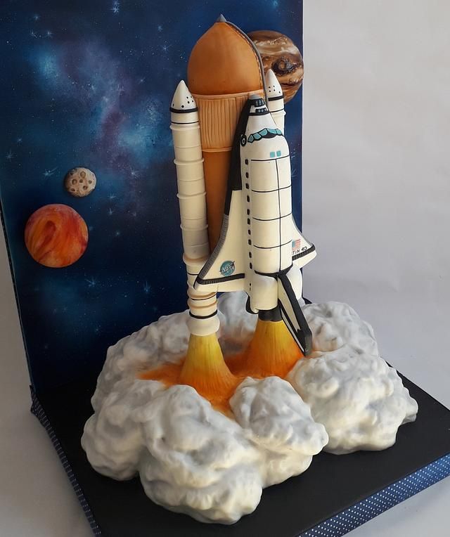 a cake made to look like a rocket ship on top of some clouds and planets