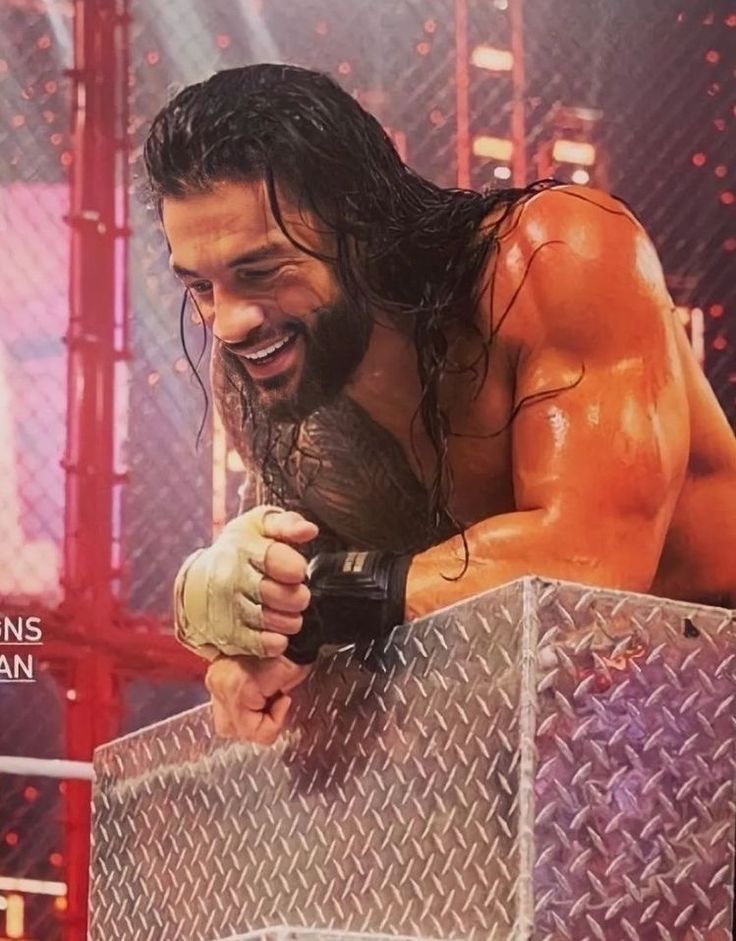 a man with long hair and no shirt holding a wrestling glove in front of a cage