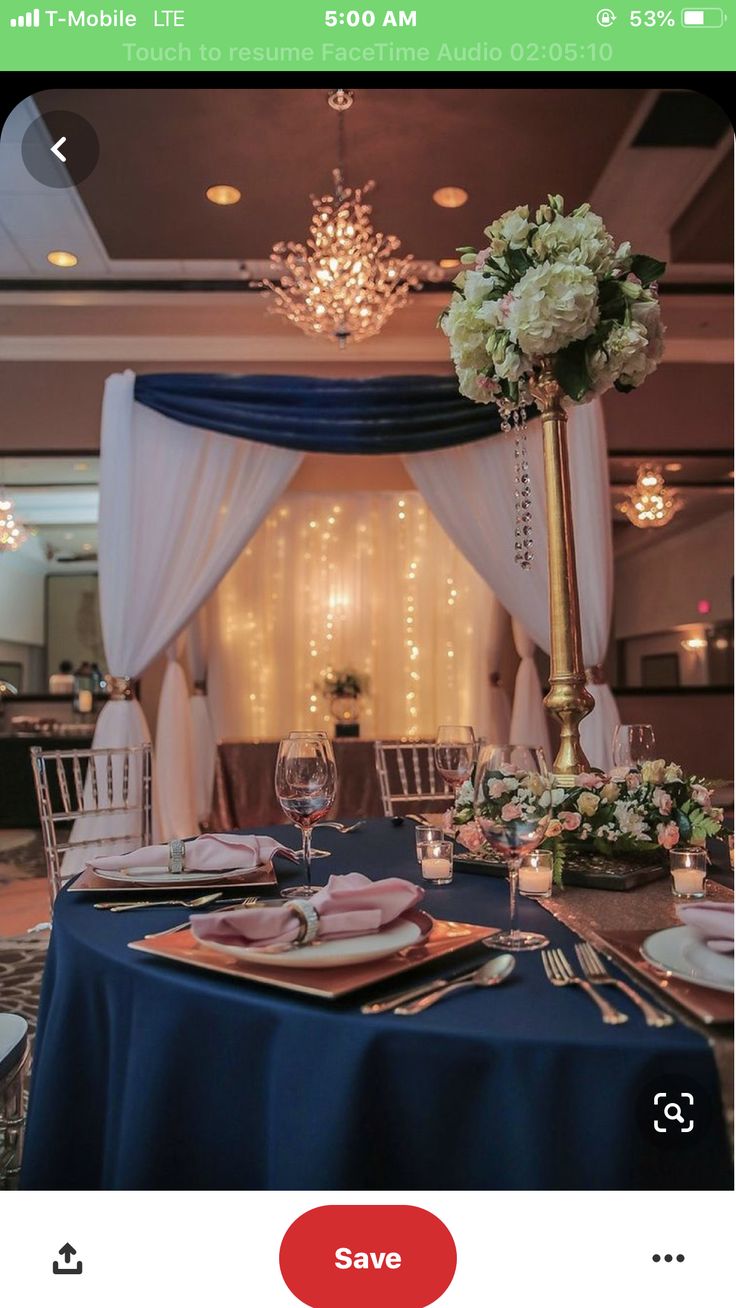 a table set up for a formal function with blue linens and white flowers on it