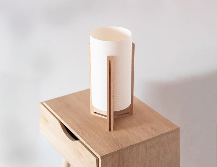 a white vase sitting on top of a wooden table next to a small drawer with drawers