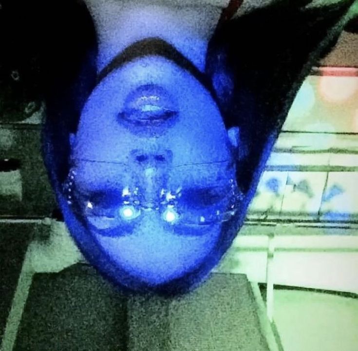 an upside down view of a person's head with blue light on it and one eye open