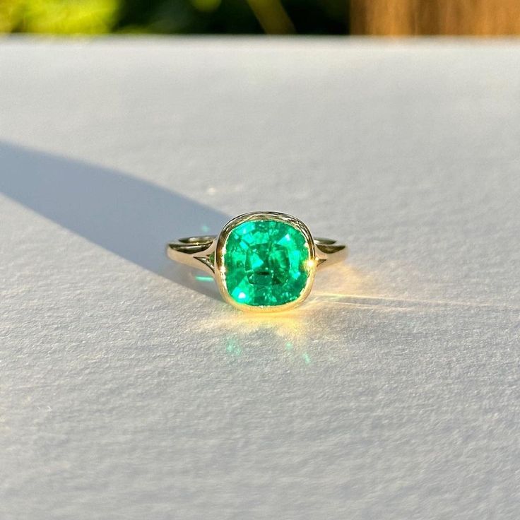 a green ring sitting on top of a white table next to a leafy tree