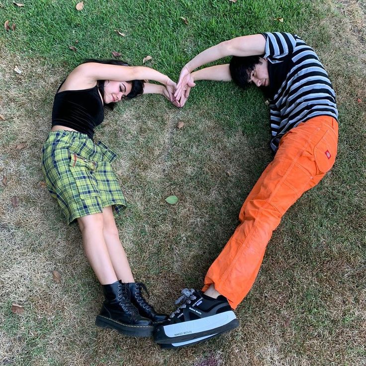 two people laying in the grass making a heart shape