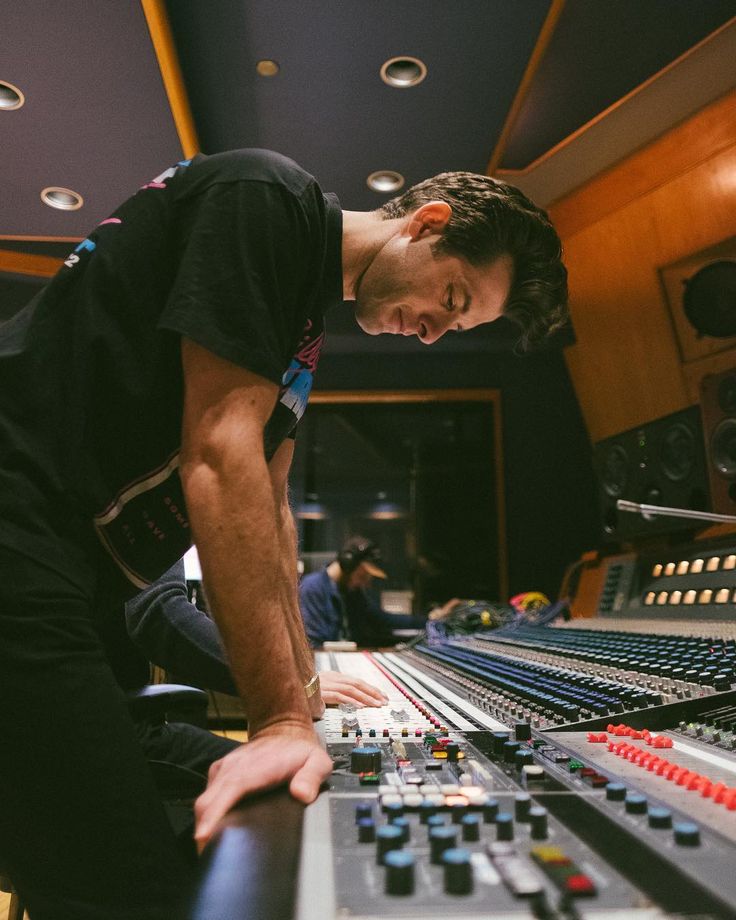 a man standing in front of a mixing desk with lots of knobs on it