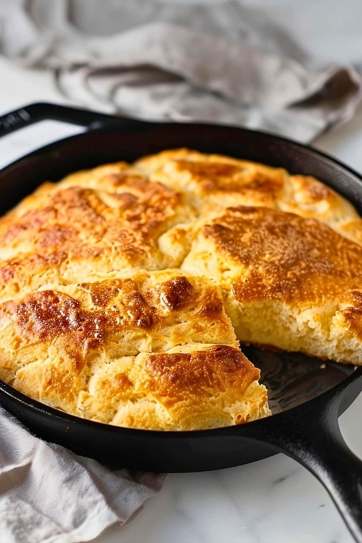 a skillet with some food in it on top of a white tablecloth and napkins