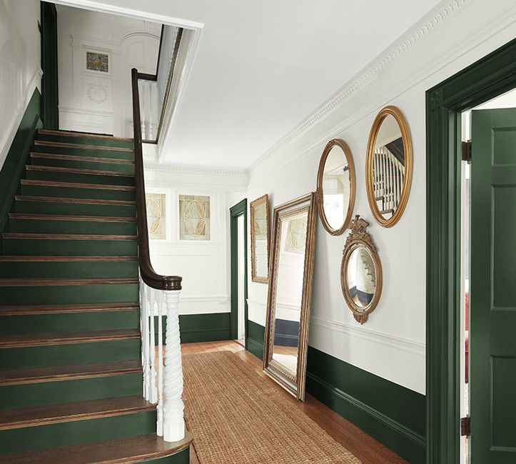 a hallway with green stairs and mirrors on the wall