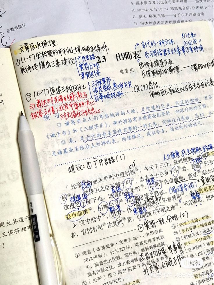 an open notebook with chinese writing and a pen