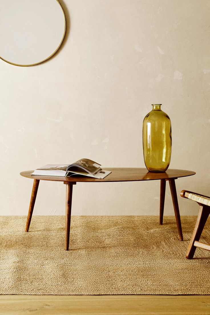 a yellow vase sitting on top of a table next to a wooden bench and chair