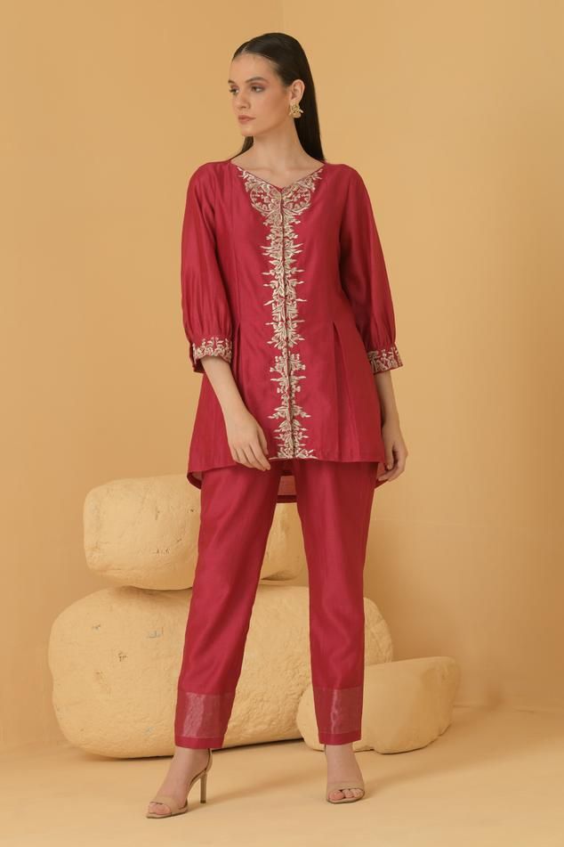 Fuchsia chanderi A-line top with puff sleeves, placement floral pattern, contrast zari, thread, sequin and pearl embroidery. Paired with straight pant with zari striped border.
Components: 2
Pattern: Embroidered
Type Of Work: Thread, Sequin, Zari and Pearl Work
Neckline: V Neck
Sleeve Type: Puff Sleeves
Fabric: Chanderi
Color: Fuchsia
Other Details: 
Attached lining
Asymmetric top hem
Length:
Top: 30 inches
Pant: 40 inches
Sleeves: 18 inches
Weight: 1.5 kgs
Top Closure: Front concealed placket
O Top With Puff Sleeves, Pearl Work, Pearl Embroidery, Asymmetric Top, Floral Embroidered Top, Color Fuchsia, Top And Pants Set, Asymmetrical Tops, Pant Set